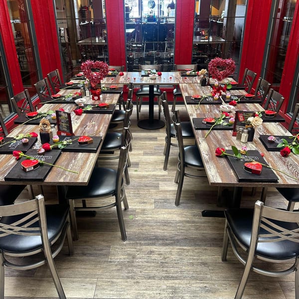 Cook'd restaurant dining room with tables set for Valentine's Day, featuring red heart decorations and roses.
