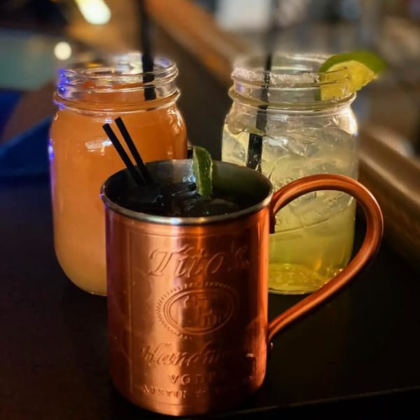 Three cocktails on a bar, including a Moscow Mule and two drinks in mason jars.